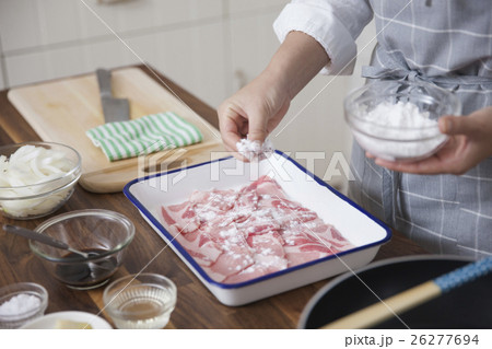 豚薄切り肉に小麦粉をまぶす女性 26277694