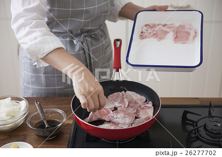 豚薄切り肉をフライパンに入れる女性 26277702