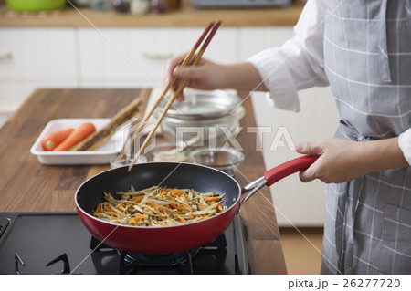 フライパンでゴボウとニンジンを炒める女性 26277720