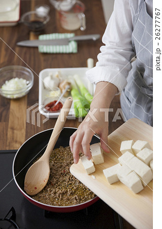 炒めた挽肉の中に豆腐を入れる女性 26277767