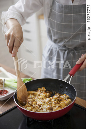 挽肉と豆腐と調味料を炒め合わせる女性 26277772