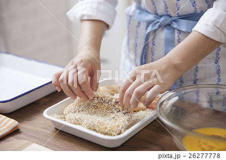 豚ロース肉にパン粉をつける女性 26277778