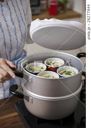 茶碗蒸しを入れた蒸し器に蓋をする女性 26277844