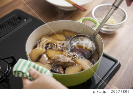 大根とブリを煮て醤油を加える女性 26277895