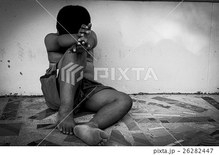 kid pauper sitting against the concrete wall 26282447