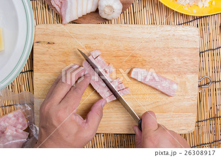 Chef cutting bacon with knife before cooking 26308917