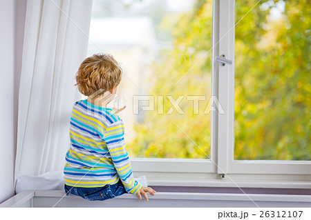 ittle kid boy sitting near window and looking on 26312107