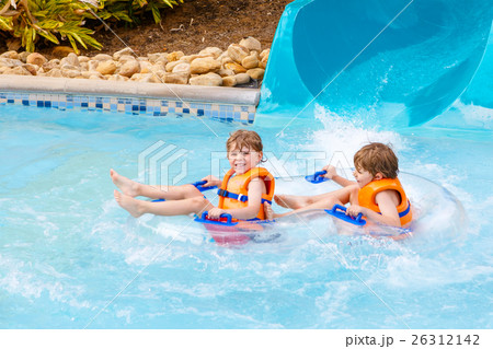 excited children in water park riding on slide 26312142