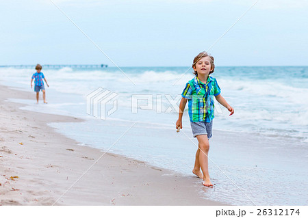 Two little kids boys running on the beach of ocean Two little kids boys running on the beach of ocean 26312174