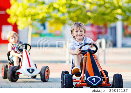 Two active little kid boys driving pedal race cars 26312187