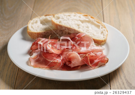 speck slices on white plate with ciabatta on old 26329437