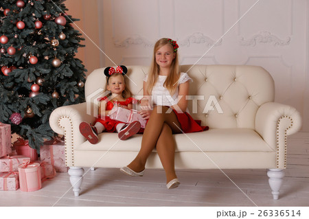 sisters girls sitting on the couch with Christmas gifts in hands sisters girls sitting on the couch with Christmas gifts in hands 26336514