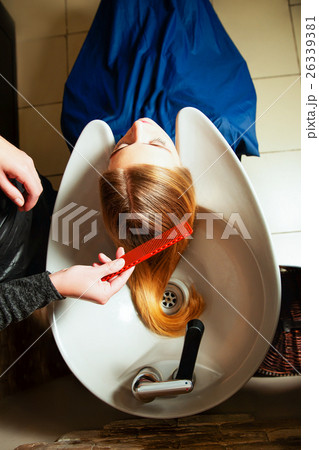 Hairdresser washing young woman's hair in salon. 26339381