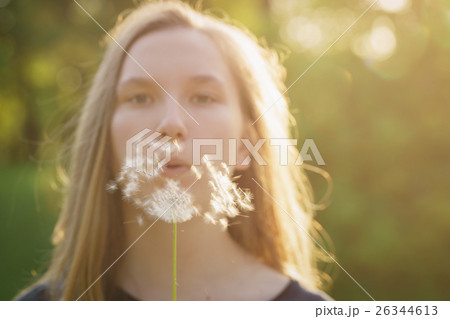 teen girl blowing dandelion to the camera teen girl blowing dandelion to the camera 26344613