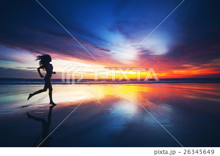 Woman running on beach at sunset 26345649