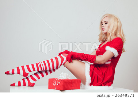 Beautiful blonde snow maiden with gift sits and 26349571