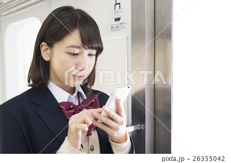 電車内でスマホをする女子高校生の写真素材