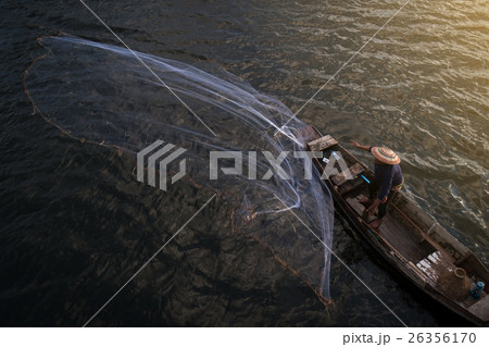 fisherman on wooden boat casting a net 26356170