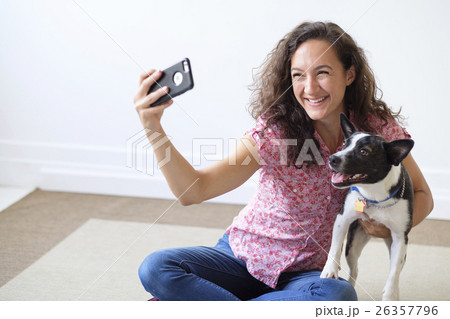 Young woman taking photograph of her dog Young woman taking photograph of her dog 26357796