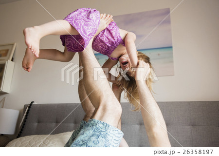Father lifting daughter (2-3) with legs 26358197