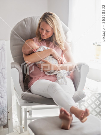 Mother sitting in armchair and holding baby son (0-1 months) 26358232