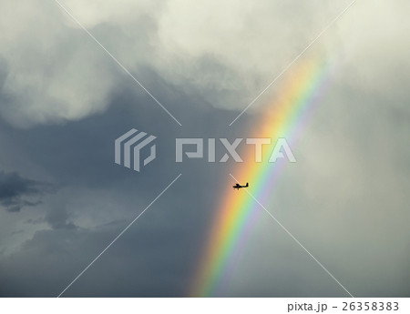 Silhouette of small plane flying through rainbow 26358383