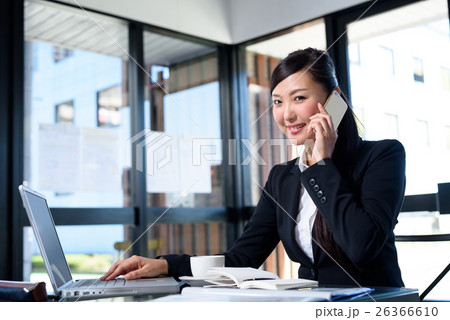 電話しながらパソコンを確認する女性 キャリアウーマン オフィス 会議イメージの写真素材