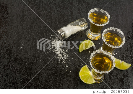 Gold tequila with lime on black background Gold tequila with lime on black background 26367052