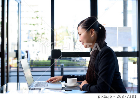 おしゃれなカフェでパソコンを扱う女性　キャリアウーマン　オフィス　カフェノマドイメージ 26377381
