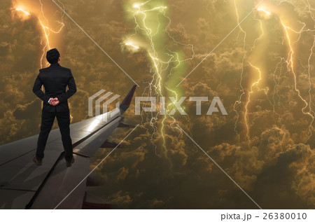 businessman standing on airplane wing and looking the thunder lightnings over the clouds and storm, Challenge business concept 26380010