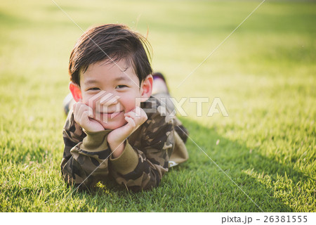 Asian child lying on greeen grass under sun light 26381555