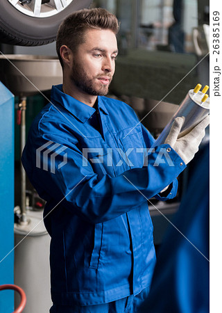 Concentrated mechanic examining oil filter 26385169