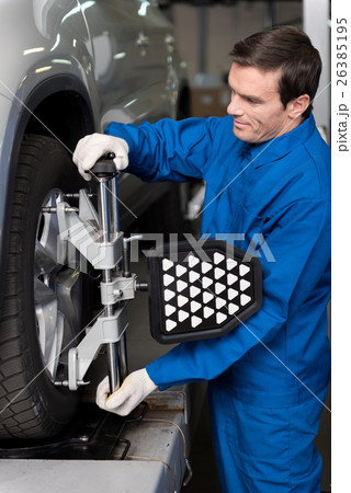 Professional mechanic adjusting automobile wheel 26385195