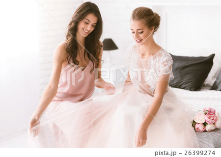 Smiling bride and bridesmaid sitting on the bed 26399274