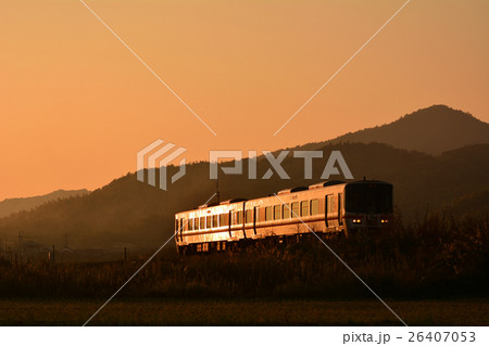 夕焼けの中走る127系普通列車 26407053