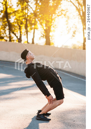 Man stretching on stadium in evening, sunset light 26440967