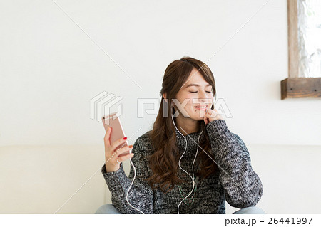 リビングのソファーでくつろぎながら音楽を聴く若い女性 26441997