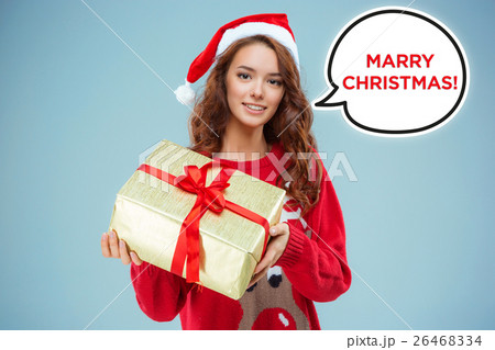 Girl dressed in santa hat with a Christmas gift Girl dressed in santa hat with a Christmas gift 26468334