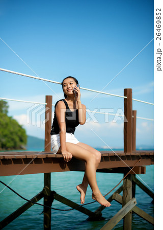 Asian girl talking on the phone at a pier Asian girl talking on the phone at a pier 26469852