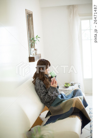 リビングのソファーでコーヒーを飲みながら音楽を聴く若い女性 26471487