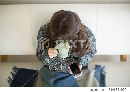 リビングのソファーでコーヒーを飲みながら音楽を聴く若い女性 リビングのソファーでコーヒーを飲みながら音楽を聴く若い女性 26471492