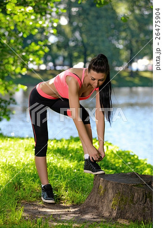 Sports girl ties laces in park, after workout training Sports girl ties laces in park, after workout training 26475904