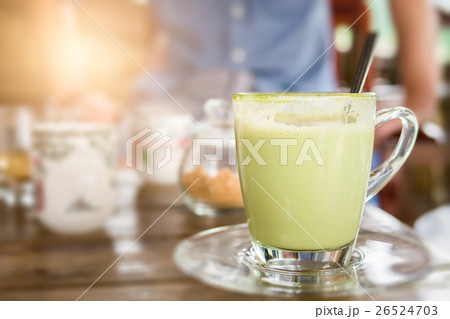 Hot green tea with milk in glass mug. 26524703