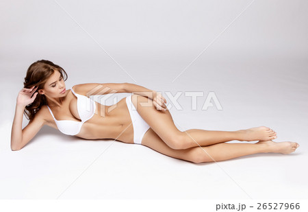 Slim tanned woman's body over gray background Slim tanned woman's body over gray background 26527966