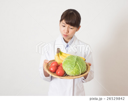 不安そうな顔をして野菜を持つ女性の写真素材