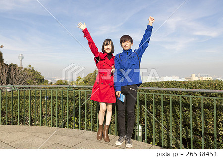 横浜観光 カップル 恋人 記念撮影 手を上げる セルフタイマー 背景マリンタワー の写真素材
