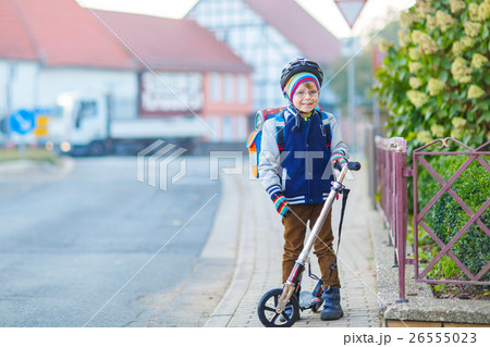 Little kid boy in helmet riding with his scooter 26555023