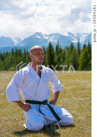Man in kimono meditating on mountains background. 26564161