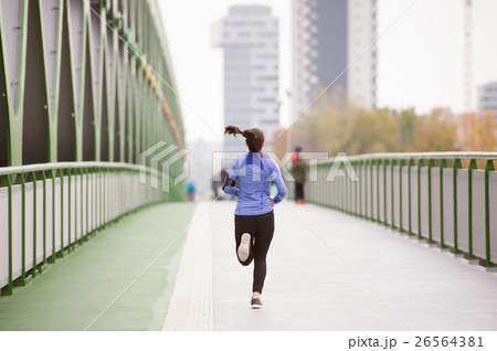 Young woman in the city running on green steel Young woman in the city running on green steel 26564381