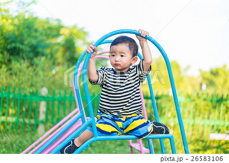 Sad little Asian kid sitting on slide 26583106